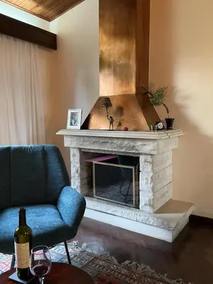 a fireplace in a living room with a blue couch and a chair at Casa Žerotín in Funchal