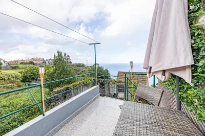 a balcony with an umbrella and a view of the ocean at Peaceful Panorama by YOUR KEY MADEIRA in Porto Moniz