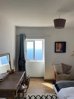 a bedroom with a bed and a table and a window at Ocean Retreat in Fajã da Ovelha