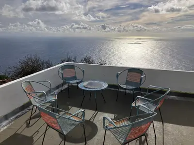 a group of chairs and a table on a balcony overlooking the ocean at Ocean Retreat in Fajã da Ovelha