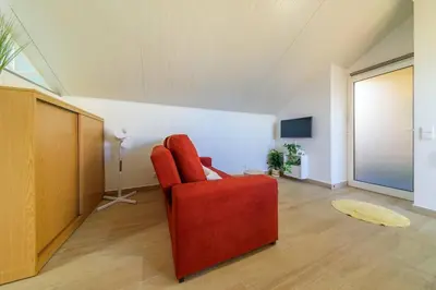 a living room with a red chair and a television at Camarata Flat by Mth in Campanário
