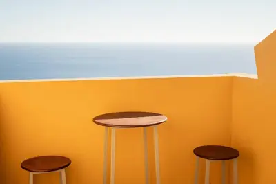 three stools in front of a wall with the ocean at Camarata Flat by Mth in Campanário