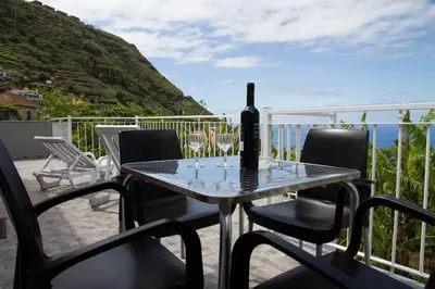 a table with a bottle of wine on a balcony at Lovely place for an excellent vacation in Arco da Calheta
