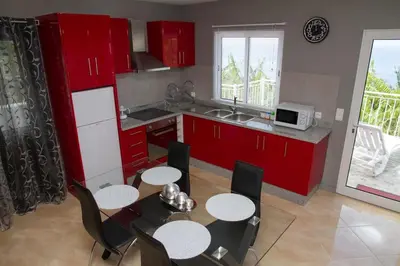 a kitchen with red cabinets and a table and chairs at Lovely place for an excellent vacation in Arco da Calheta