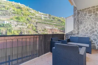 a balcony with two blue chairs and a mountain at Villa Holiday Sun by Holiday Rental Madeira in Ponta do Sol