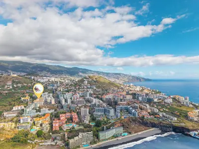 a hot air balloon flying over a city next to the ocean at Famoso Grand Stay - Free Parking in Funchal