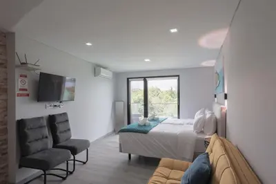 a bedroom with a bed and two chairs and a tv at Casa da Mãe in Santana