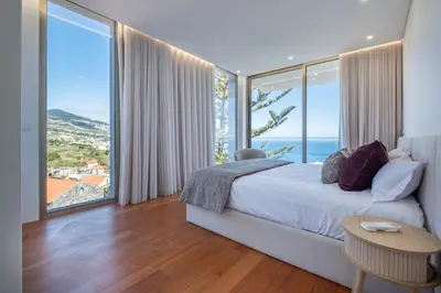 a bedroom with a bed and large glass windows at Villa Rada, by Pausa Holiday Rentals in Estreito da Calheta