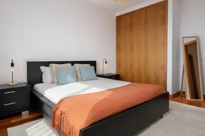 a bedroom with a large bed and a wooden cabinet at Blue Horizon Apartment by An Island Apart in Caniço