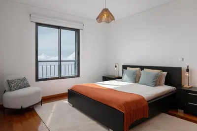 a bedroom with a bed and a window and a chair at Blue Horizon Apartment by An Island Apart in Caniço