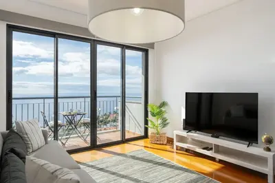 a living room with a tv and a large window at Blue Horizon Apartment by An Island Apart in Caniço