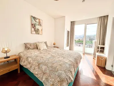 a bedroom with a bed and a large window at The Luzia House - 4BR Villa - AC, large kitchen, living room, free parking, gardens, terraces, sun exposure all day - Coliving in Funchal