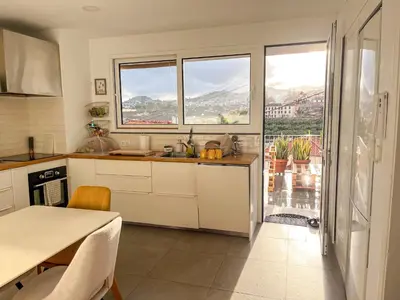 a kitchen with white cabinets and a table and windows at The Luzia House - 4BR Villa - AC, large kitchen, living room, free parking, gardens, terraces, sun exposure all day - Coliving in Funchal