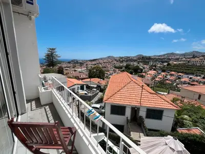 a balcony with two chairs and a view of a city at The Luzia House - 4BR Villa - AC, large kitchen, living room, free parking, gardens, terraces, sun exposure all day - Coliving in Funchal