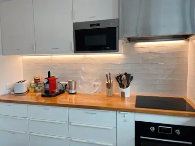 a kitchen with white cabinets and a wooden counter top at The Luzia House - 4BR Villa - AC, large kitchen, living room, free parking, gardens, terraces, sun exposure all day - Coliving in Funchal