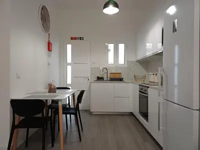 a kitchen with white cabinets and a table and chairs at Sunset Cottage in Ponta do Sol