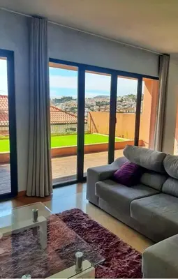 a living room with a couch and a large window at Private Garden and Pool in the Heart of Funchal in Funchal