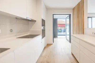 a kitchen with white cabinets and a wooden floor at Sunny Luxury Apartment Canico in Caniço