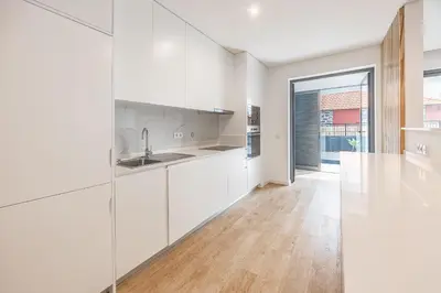 a kitchen with white cabinets and a wooden floor at Sunny Luxury Apartment Canico in Caniço
