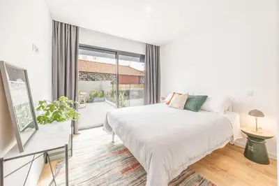 a white bedroom with a bed and a large window at Sunny Luxury Apartment Canico in Caniço