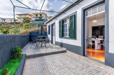 a house with a patio with a table and chairs at Serenity Sao Roque 2 Bedroom House in Funchal with Parking in Funchal