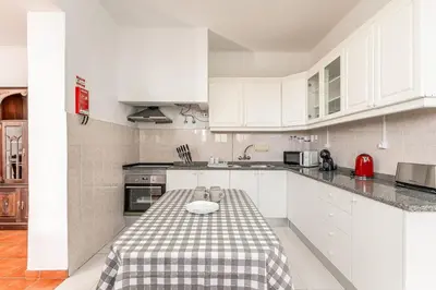 a kitchen with white cabinets and a table with a plate on it at Serenity Sao Roque 2 Bedroom House in Funchal with Parking in Funchal