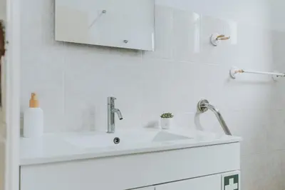 a white sink in a white tiled bathroom at Serenity Sao Roque 2 Bedroom House in Funchal with Parking in Funchal