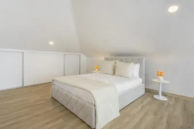 a white bedroom with a white bed and a table at Sky and Sea Haven in Santa Cruz