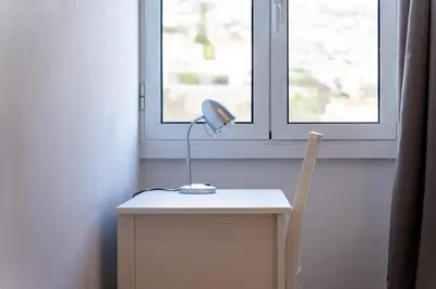 a desk with a lamp and a chair next to a window at GuestReady - Wake Up to the Heartbeat of Madeira in Funchal