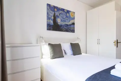 a bedroom with a white bed and a painting on the wall at GuestReady - Wake Up to the Heartbeat of Madeira in Funchal