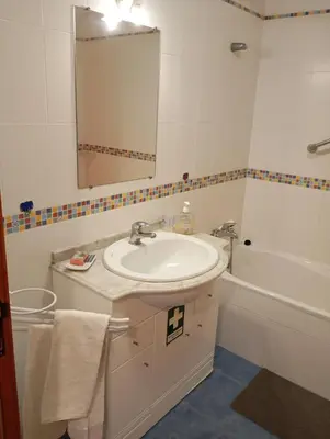 a bathroom with a sink and a tub and a mirror at Aroma do Mar in Caniço