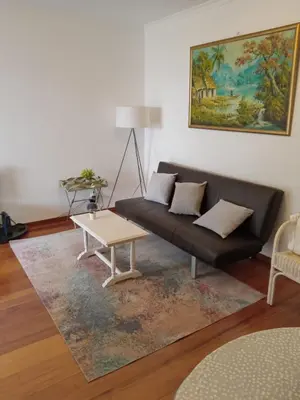 a living room with a black couch and a table at Aroma do Mar in Caniço