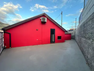 a red building with a door in a parking lot at Casa Joao Batista em Machico in Machico