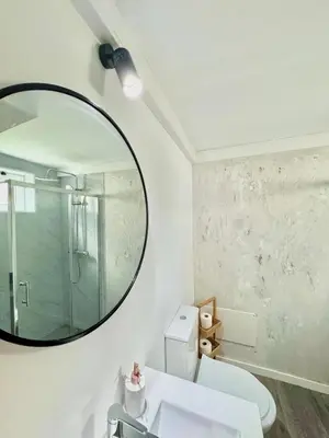 a bathroom with a mirror and a white toilet at The West House in Calheta