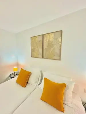 two beds in a bedroom with two yellow pillows at The West House in Calheta
