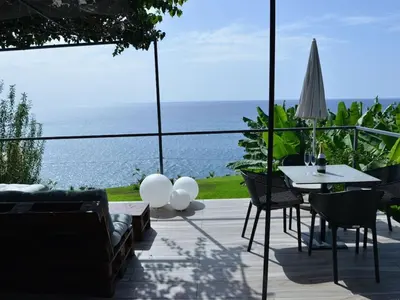 a patio with a table and chairs and the ocean at Quinta Golfinho - Villa Rosa in Arco da Calheta