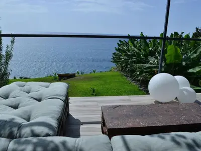 a living room with a couch and a view of the ocean at Quinta Golfinho - Villa Rosa in Arco da Calheta