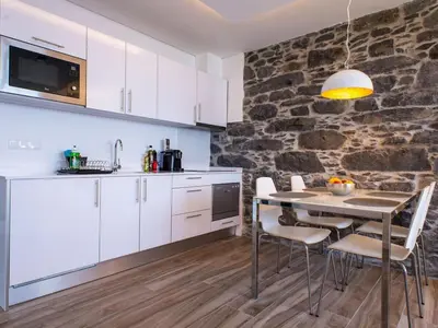 a kitchen with a table and chairs and a stone wall at Quinta Golfinho - Villa Rosa in Arco da Calheta