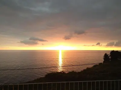 a sunset over the ocean with the sun setting at Holoiday home Casa Estrelizia in Arco da Calheta