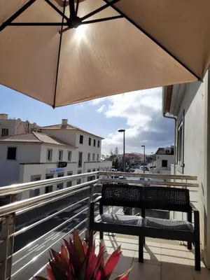 a bench sitting on a balcony with an umbrella at SeaView in Porto Santo