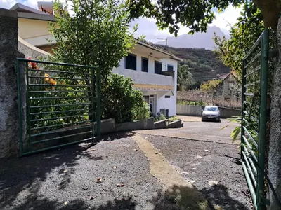 a gate to a house with a car parked in the driveway at Northern Air House in São Vicente