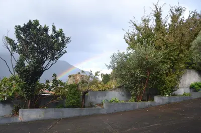 a rainbow in the sky with trees and a wall at Northern Air House in São Vicente