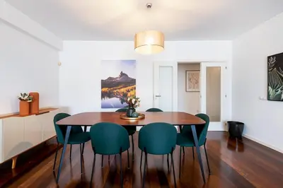 a dining room with a wooden table and green chairs at GuestReady – Madeira escape with ocean view in Funchal