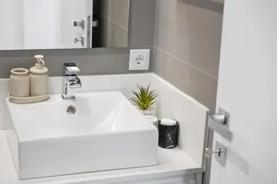a bathroom with a white sink and a mirror at Modern Studio Steps From Beach in Ponta do Sol