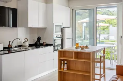 a kitchen with white cabinets and a counter top at Modern Studio Steps From Beach in Ponta do Sol