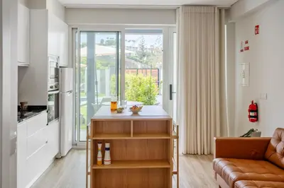 a living room with a couch and a kitchen at Modern Studio Steps From Beach in Ponta do Sol