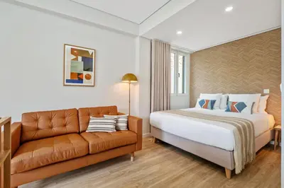a bedroom with a bed and a couch at Modern Studio Steps From Beach in Ponta do Sol