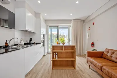 a kitchen and a living room with a couch at Modern Studio Steps From Beach in Ponta do Sol