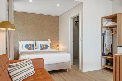 a bedroom with a bed and a couch at Modern Studio Steps From Beach in Ponta do Sol