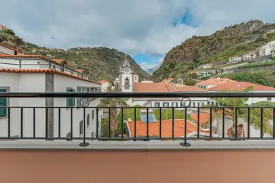 a balcony with a view of a building and mountains at Ribeira brava - duplex sea view in Ribeira Brava